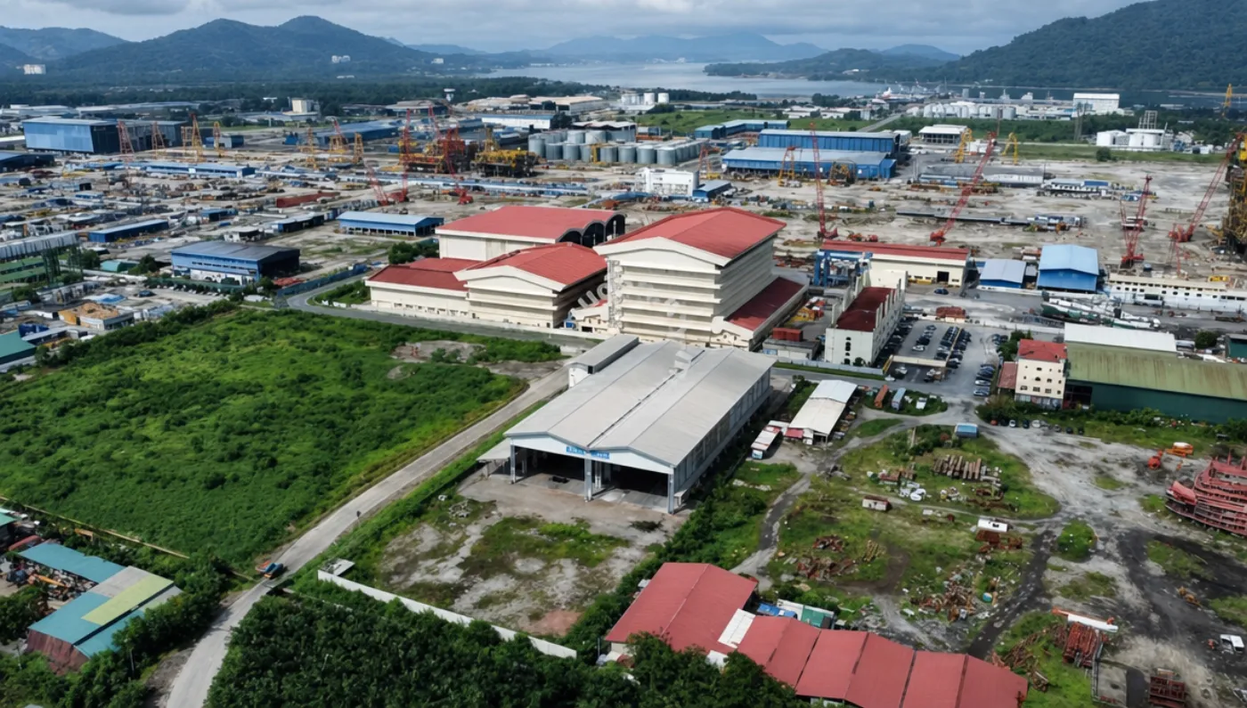 Aerial view of the working coastal fabrication yard with workshops, gantry cranes, and blast yards.